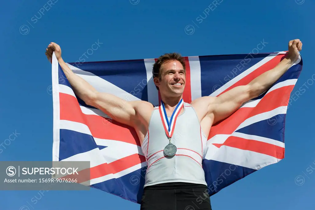 Male athlete on winner´s podium, holding up British flag