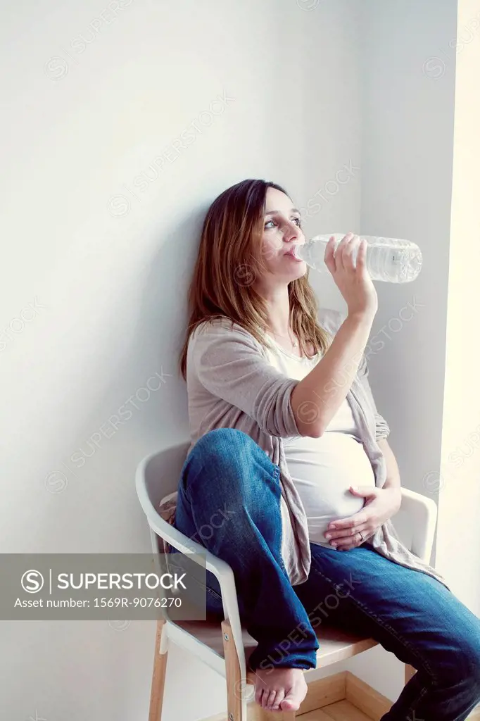 Pregnant woman drinking water from bottle
