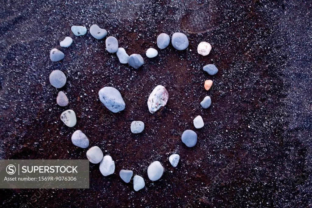 Pebbles arranged in heart shape on black sand