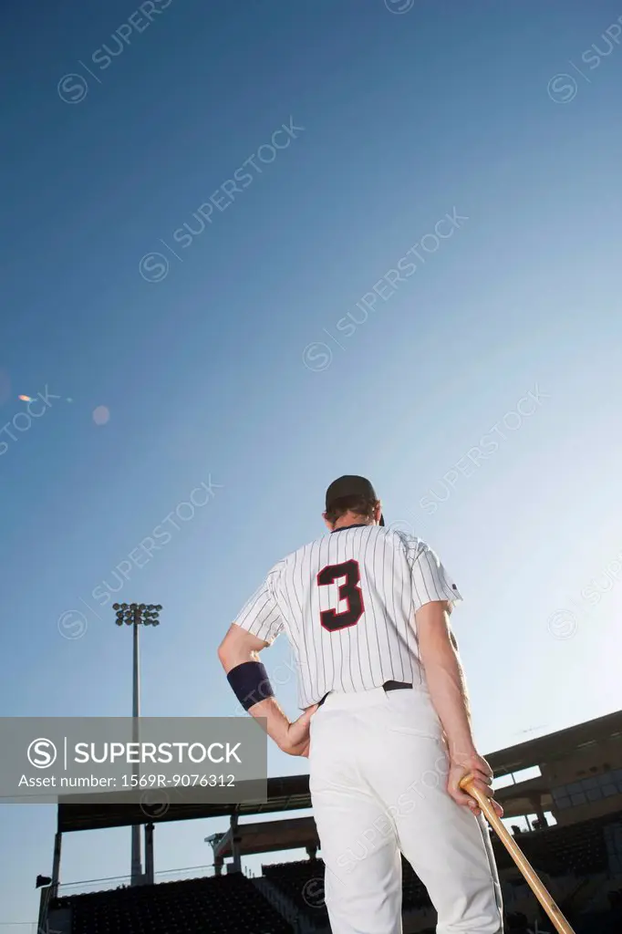 Baseball player standing with hand on hip, rear view