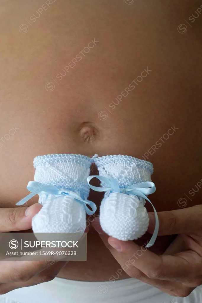 Pregnant woman holding baby booties, cropped