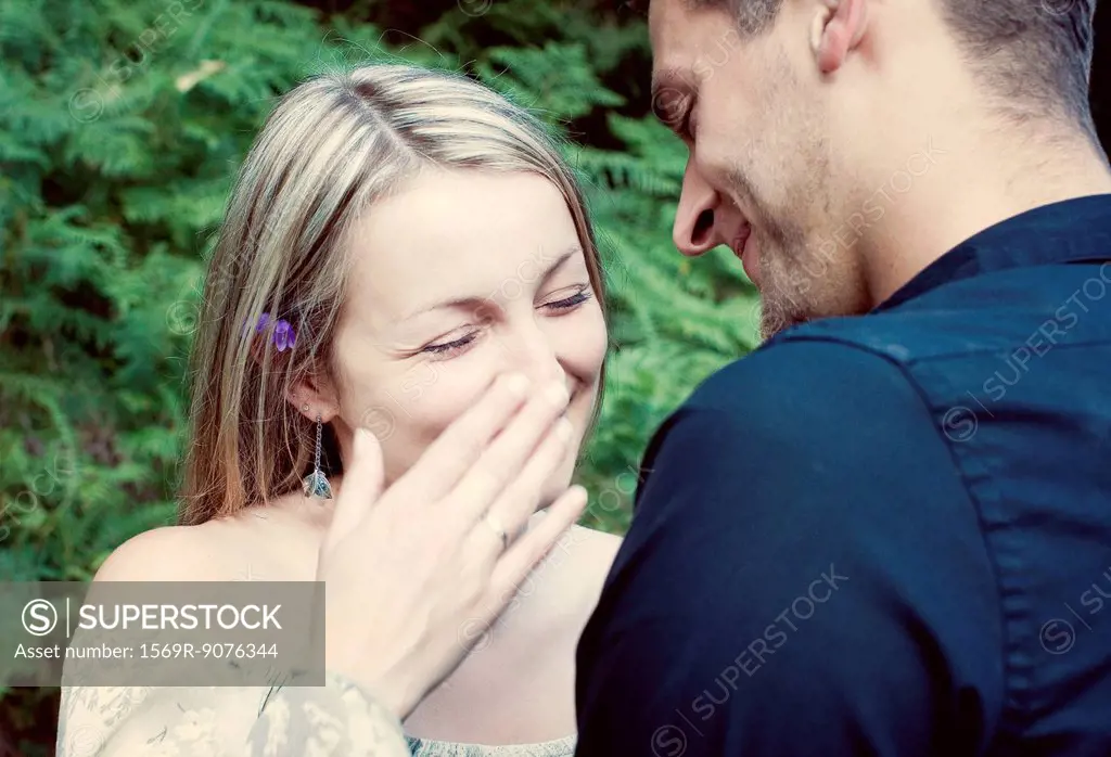 Couple together outdoors, woman laughing and covering her mouth