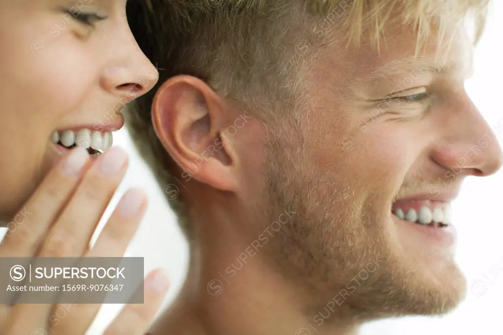 Woman whispering in man´s ear, close_up