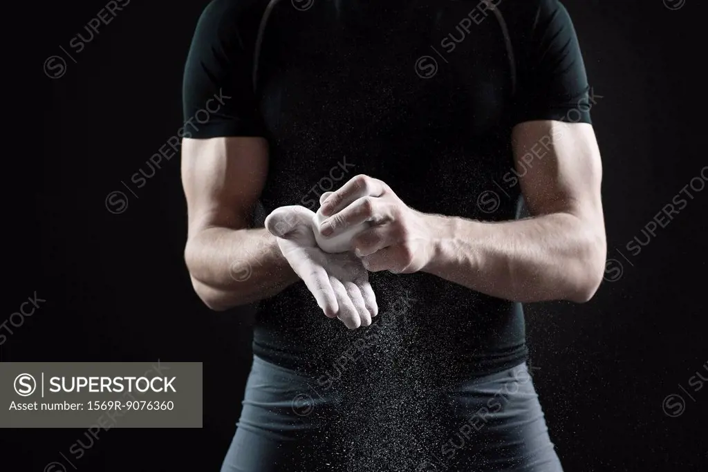 Male athlete applying chalk to hands, mid section
