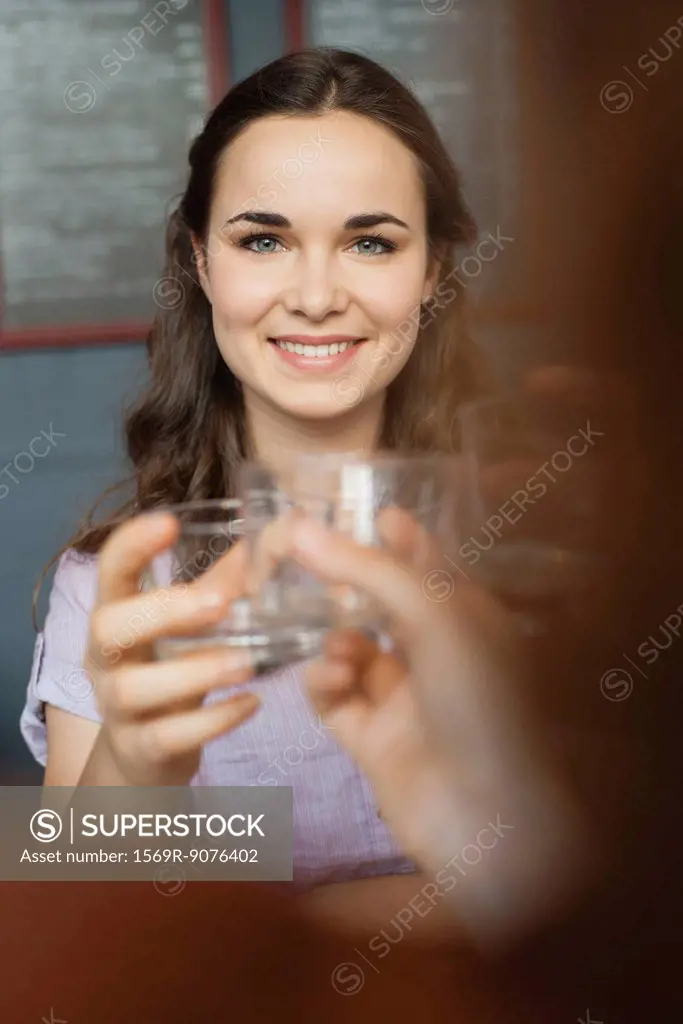 Young woman raising glass with friend