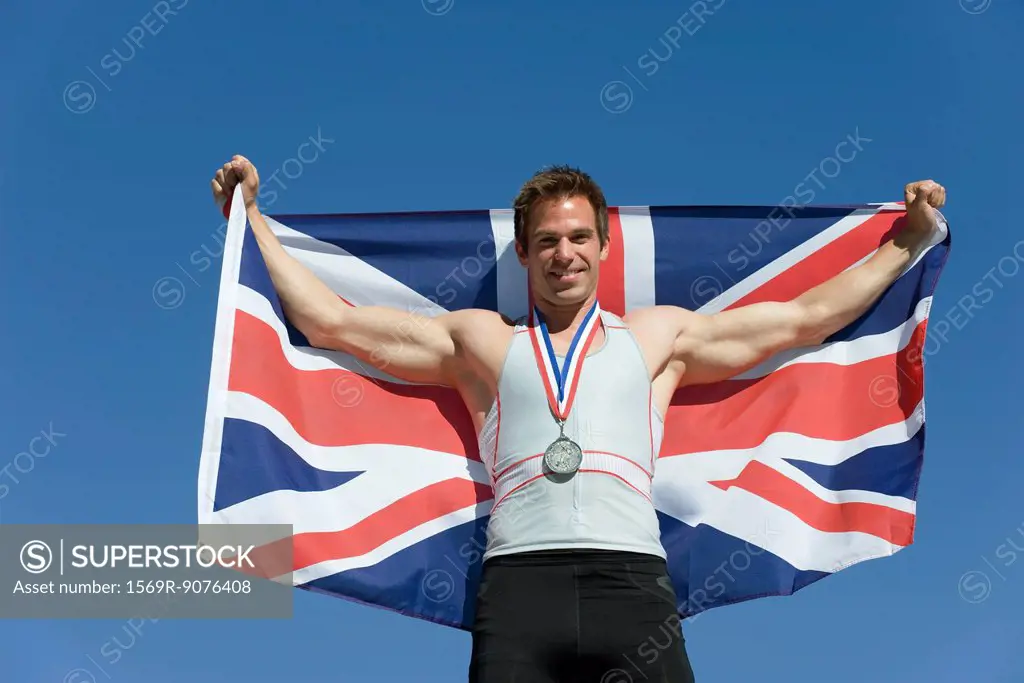 Male athlete on winner´s podium, holding up British flag