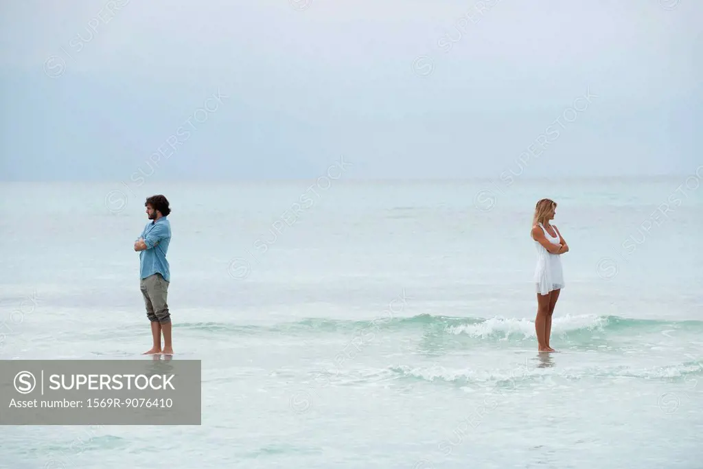 Couple standing apart in sea with backs turned toward each other