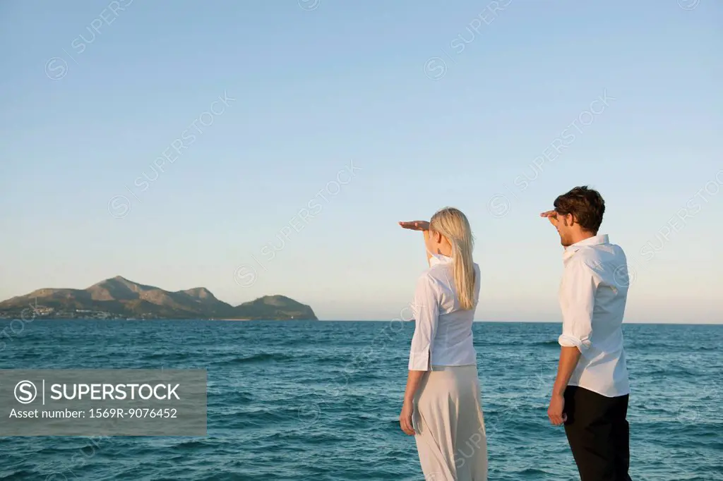 Couple standing by water looking at view