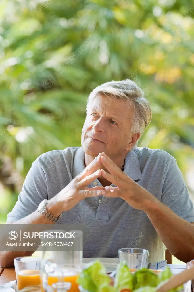 Senior man having breakfast outdoors, portrait