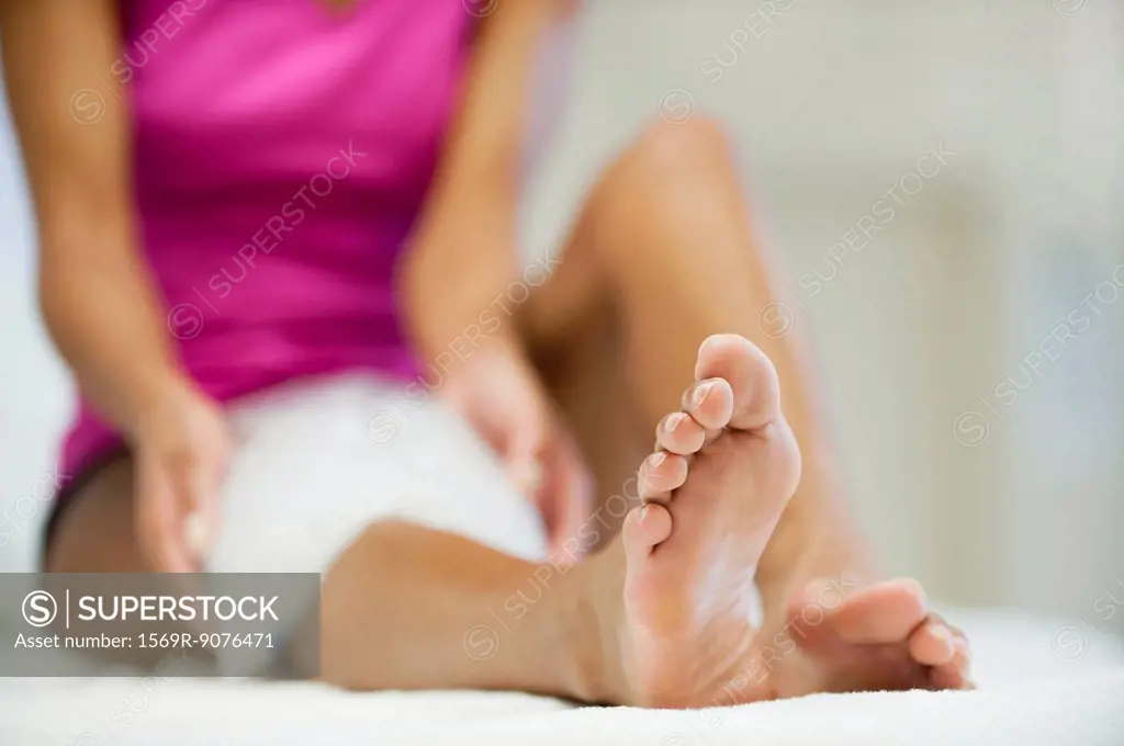 Woman sitting with ice pack on knee, focus on foreground