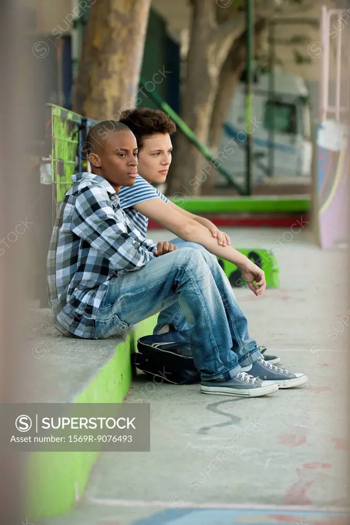 Young men sitting on sidewalk