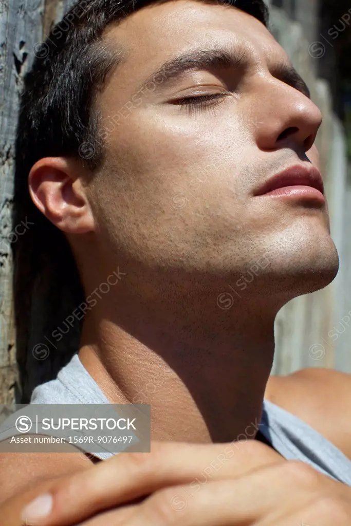 Mid_adult man sunbathing with eyes closed