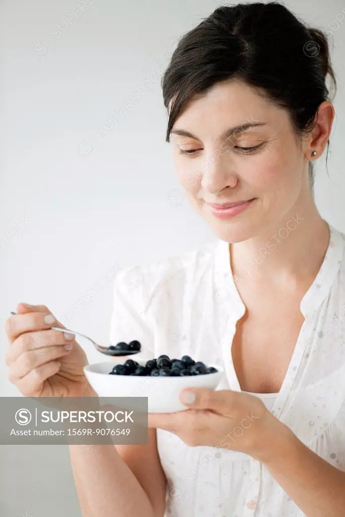 Woman eating bowl of fresh blueberries