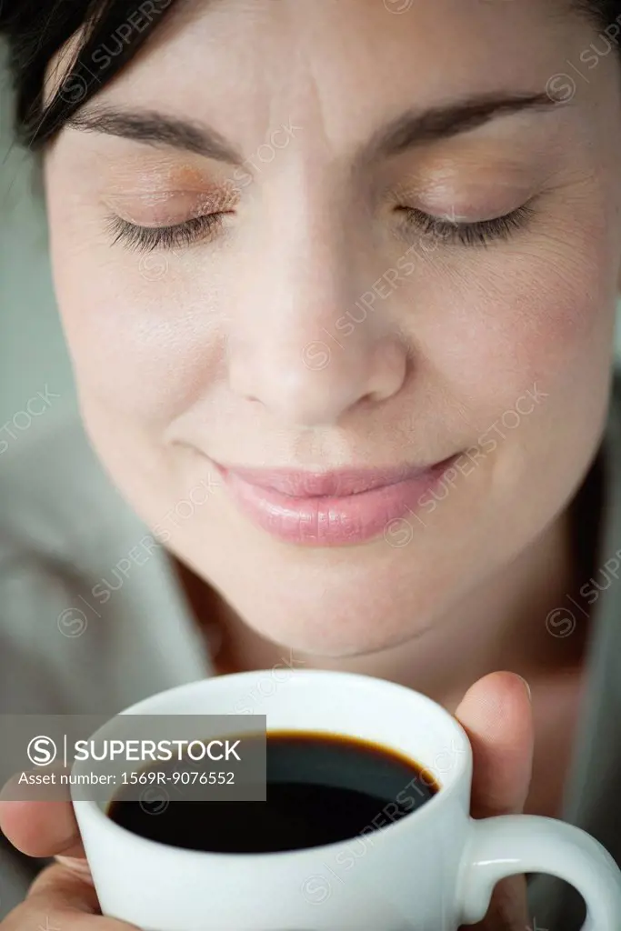 Mid_adult woman smelling cup of coffee