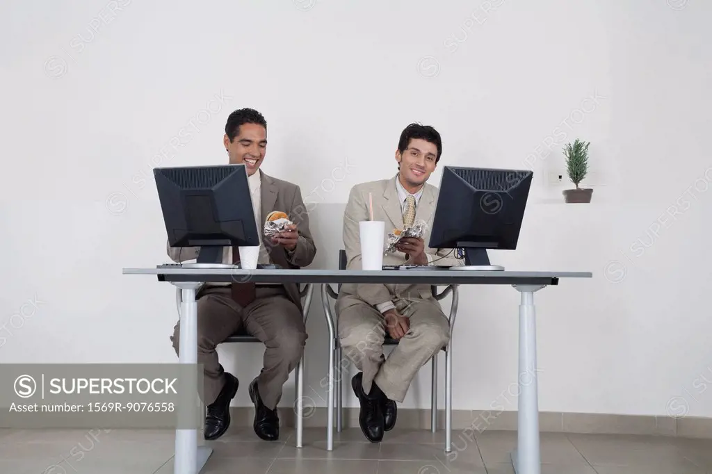 Businessmen eating fast food at desk in office