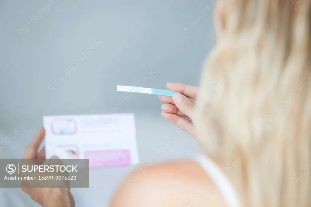 Woman reading pregnancy test, cropped
