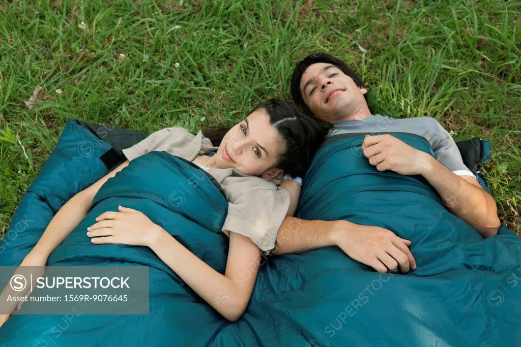 Young couple sharing sleeping bag in field