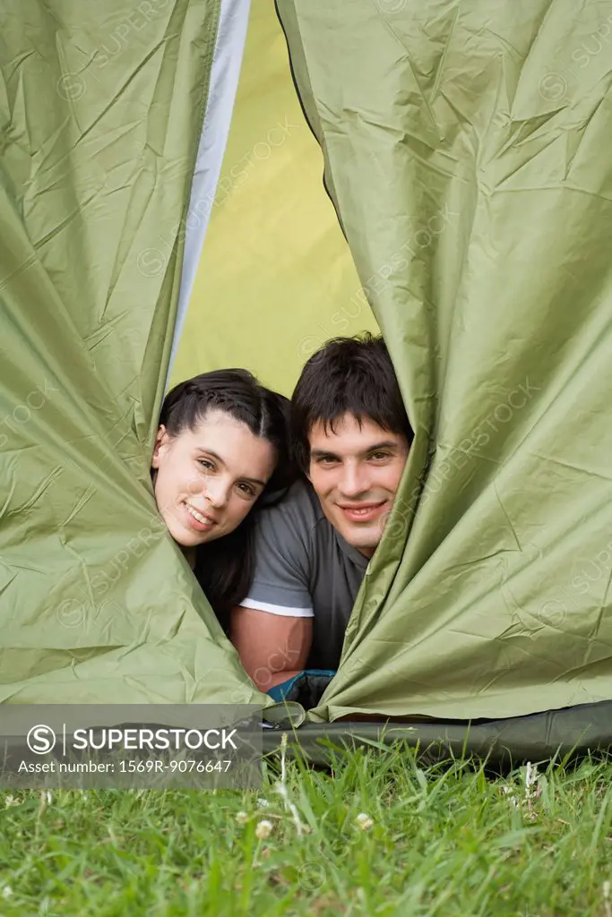 Young couple peeking out from tent