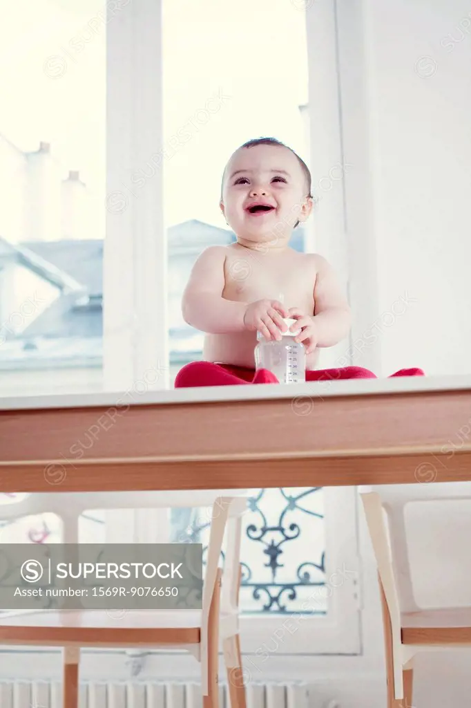 Semi_naked infant sitting on table