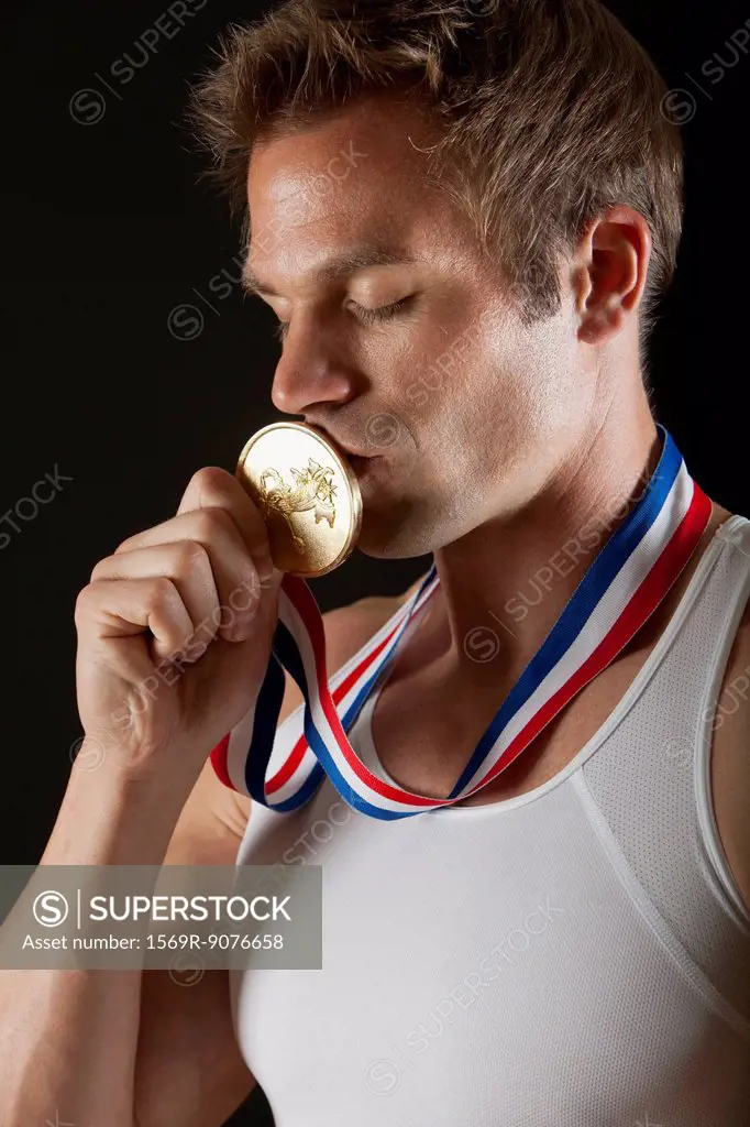 Male gymnast kissing gold medal, portrait