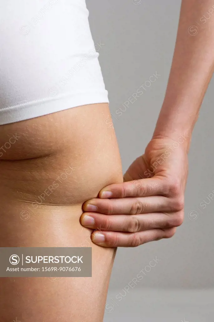 Woman pinching own buttock, cropped