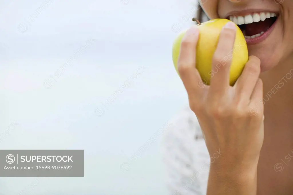 Woman eating apple, cropped
