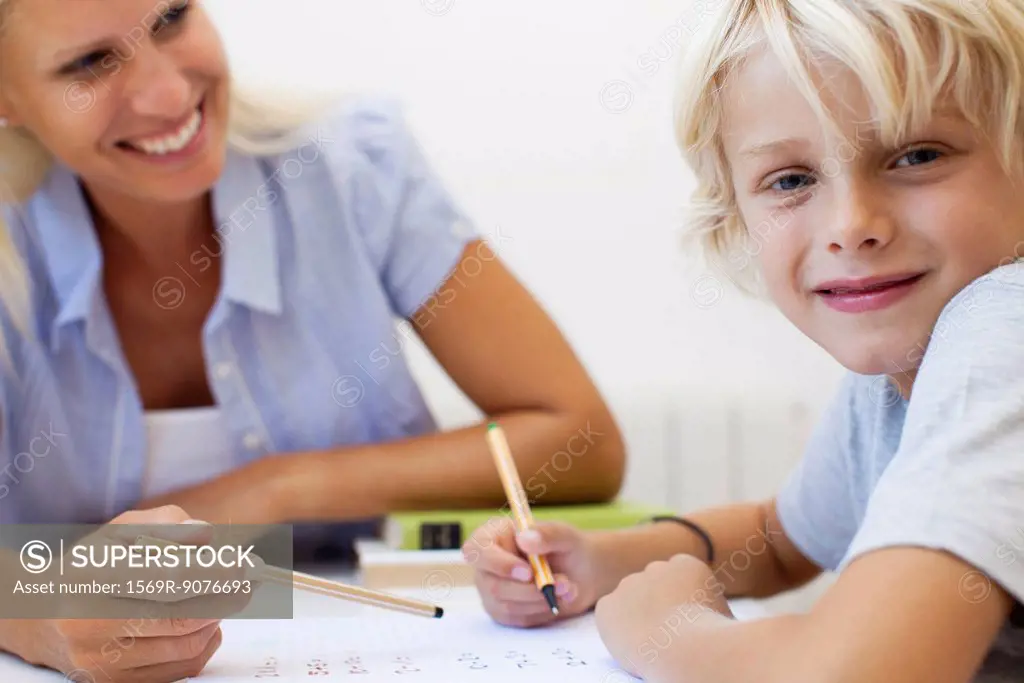 Boy doing homework, smiling at camera