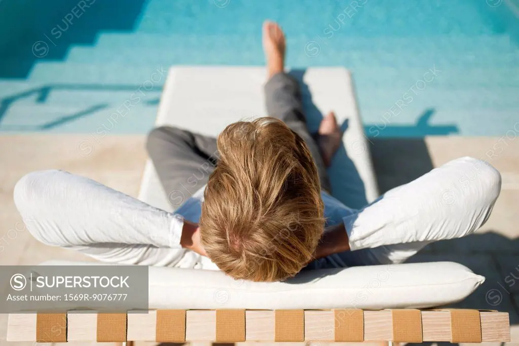 Man relaxing on lounge chair beside pool