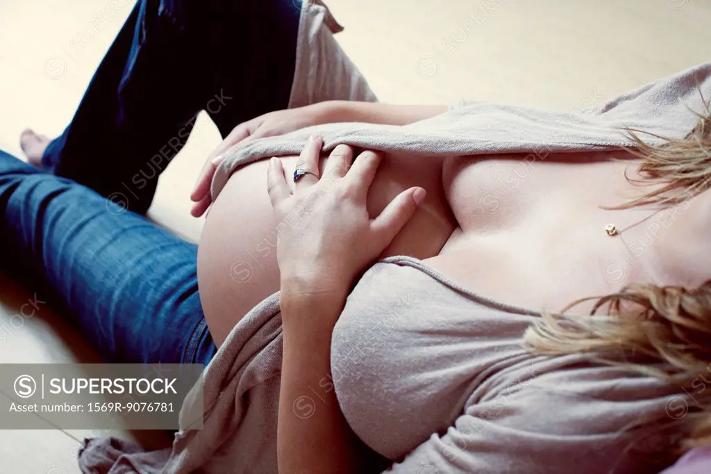 Pregnant woman caressing abdomen, mid section, high angle view