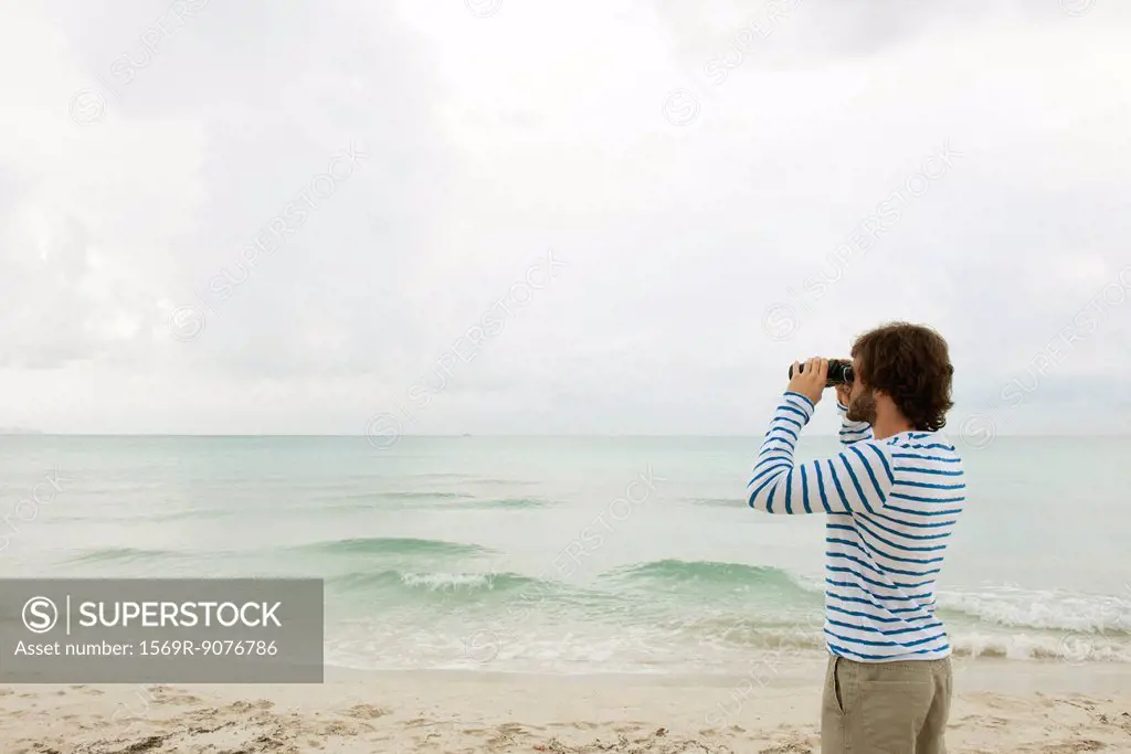 Man looking at view through binoculars