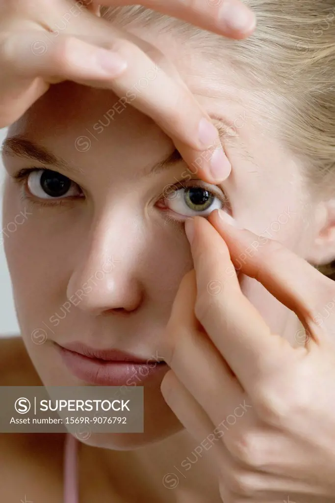 Young woman putting in contact lens