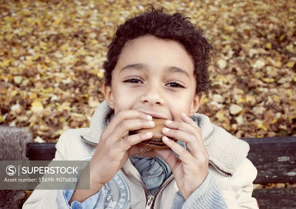 Boy eating macaroon, portrait