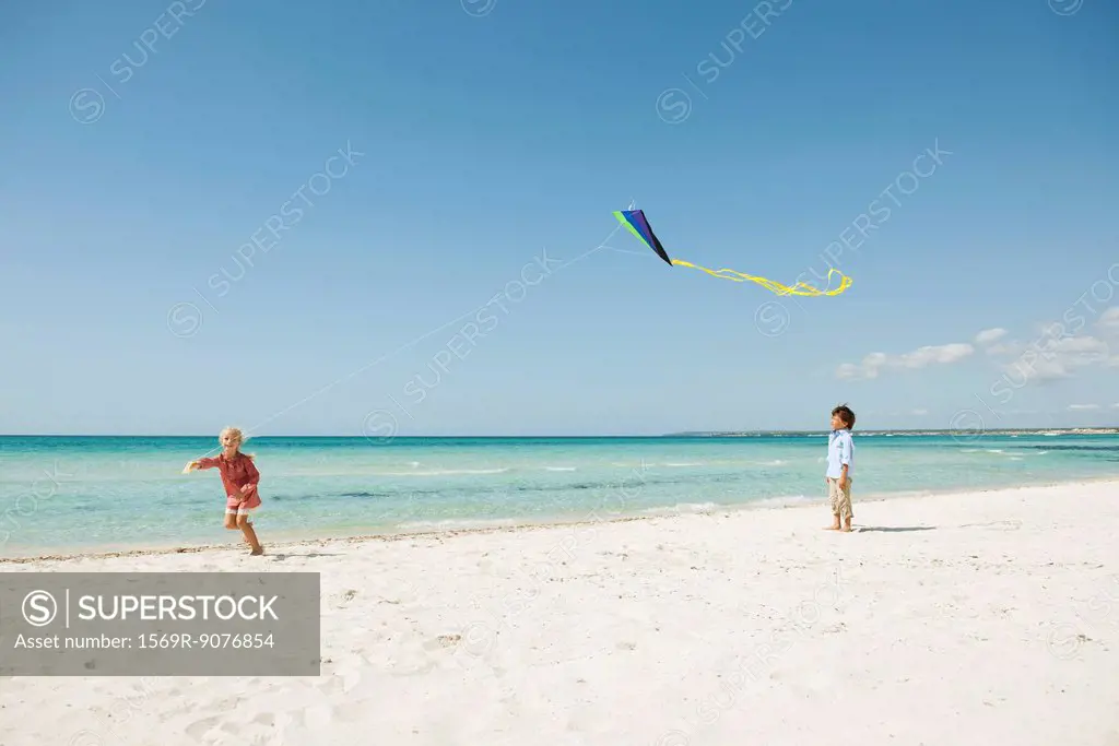 Boy watching girl flying kite