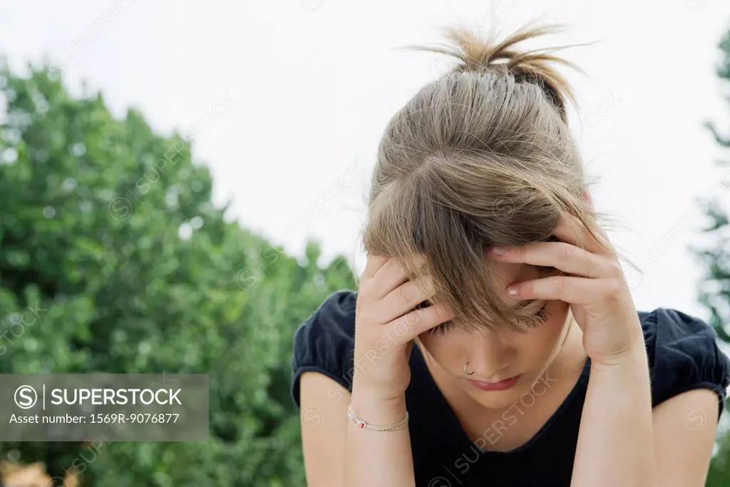 Upset young woman holding head and looking down