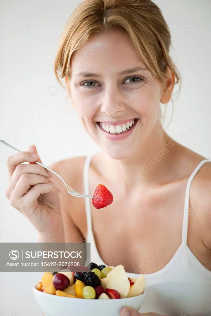 Young woman eating fruit salad, portrait