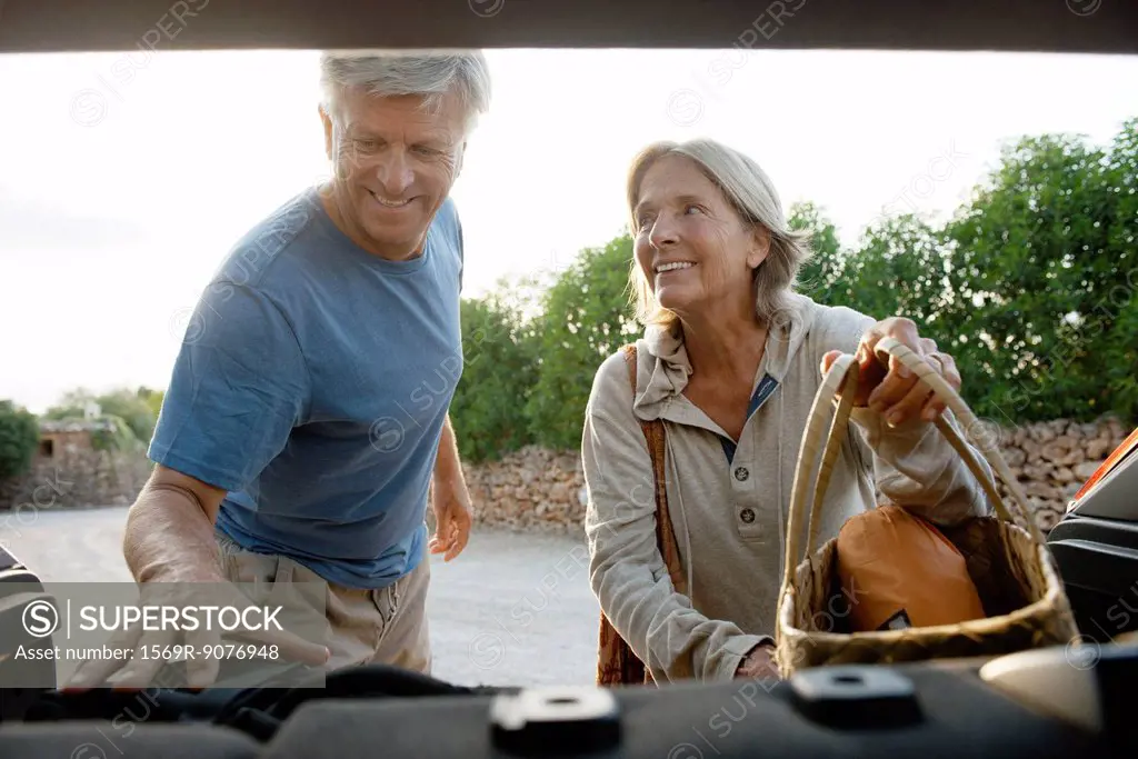 Senior couple loading bags into car
