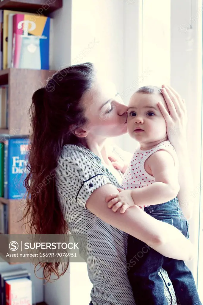 Mother kissing baby girl, portrait