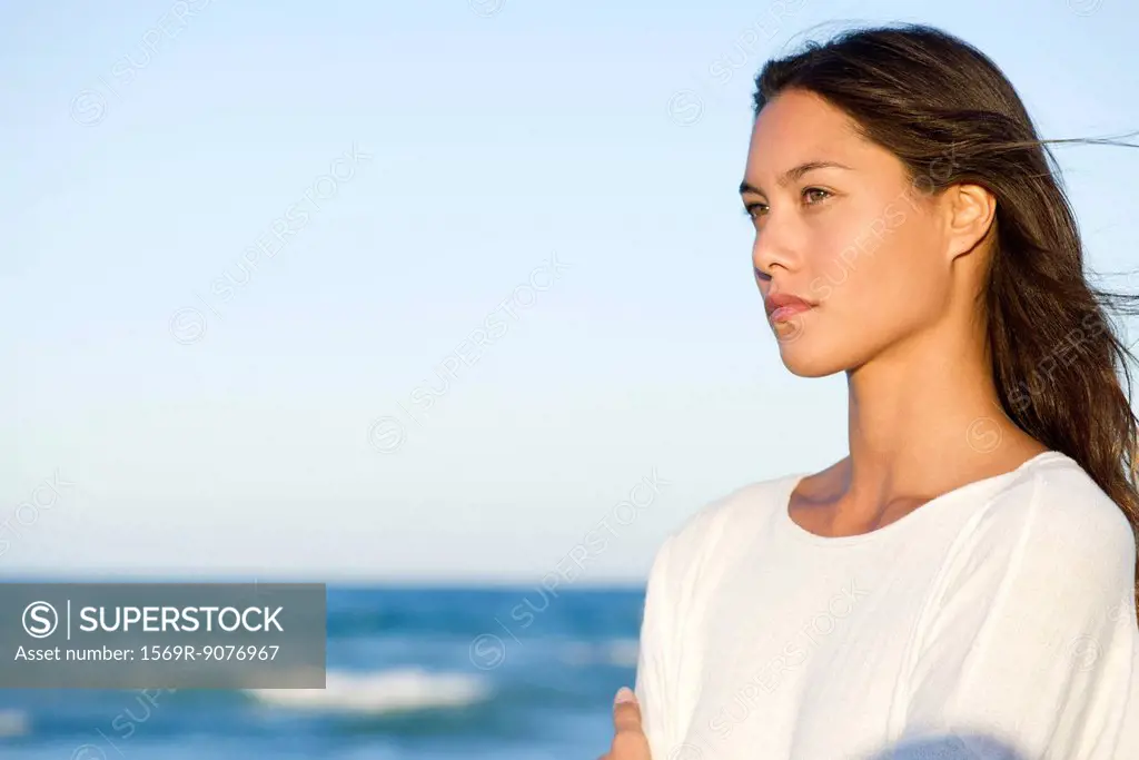 Young woman contemplating over ocean view, portrait