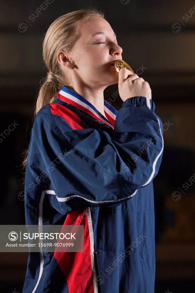 Female athlete kissing gold medal