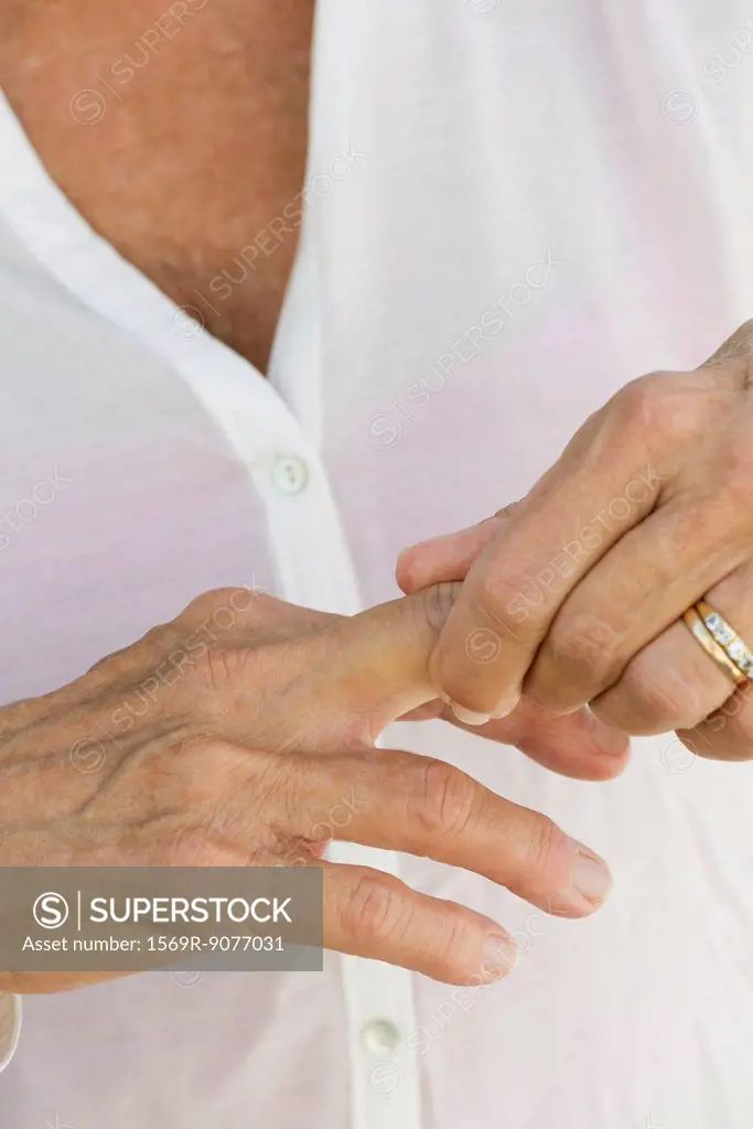 Senior woman rubbing knuckles, cropped