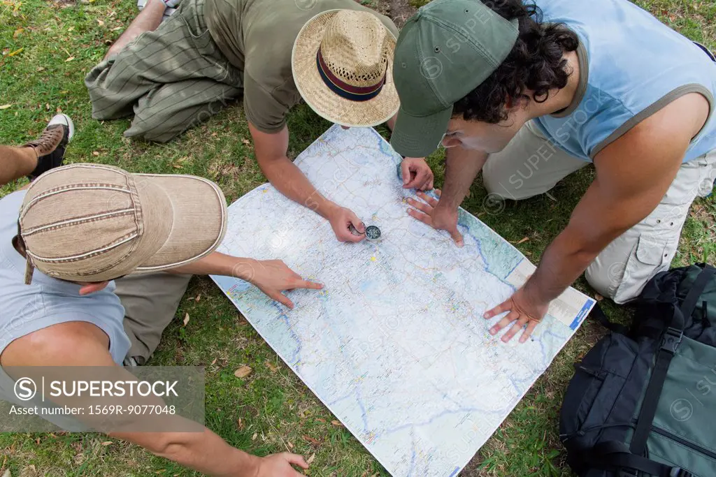 Hikers using compass and looking at map together, high angle view