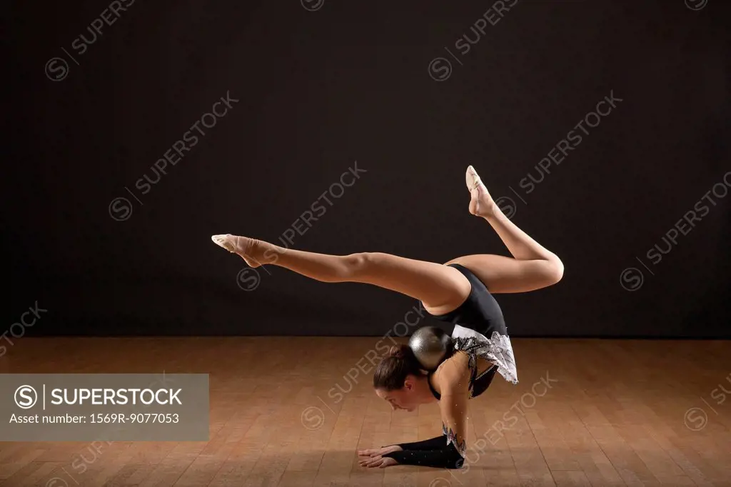 Gymnast bending backwards, balancing ball with head