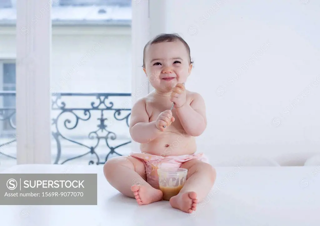 Infant playing with spoon while eating, portrait