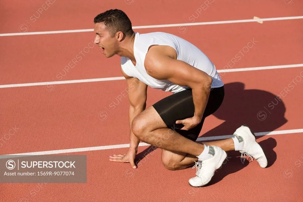 Injured runner kneeling on running track