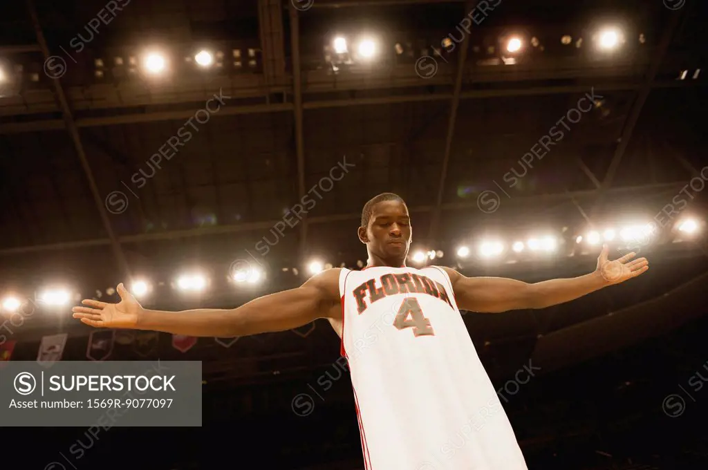 Basketball player standing with arms out, low angle view