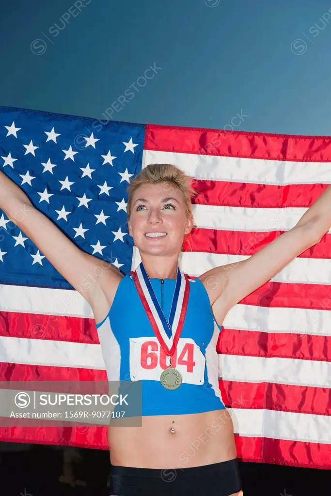 Female medal winner holding up American flag in victory
