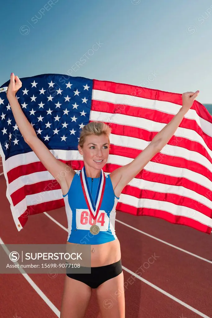 Female medal winner holding up American flag in victory