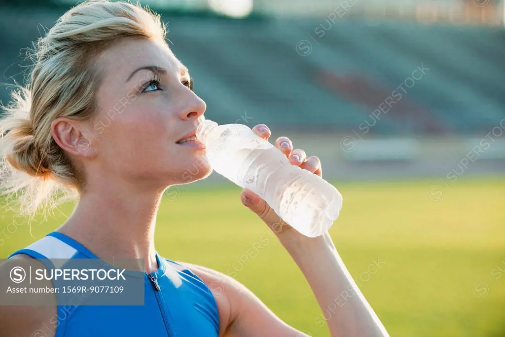 Young woman hydrating, taking break from exercising