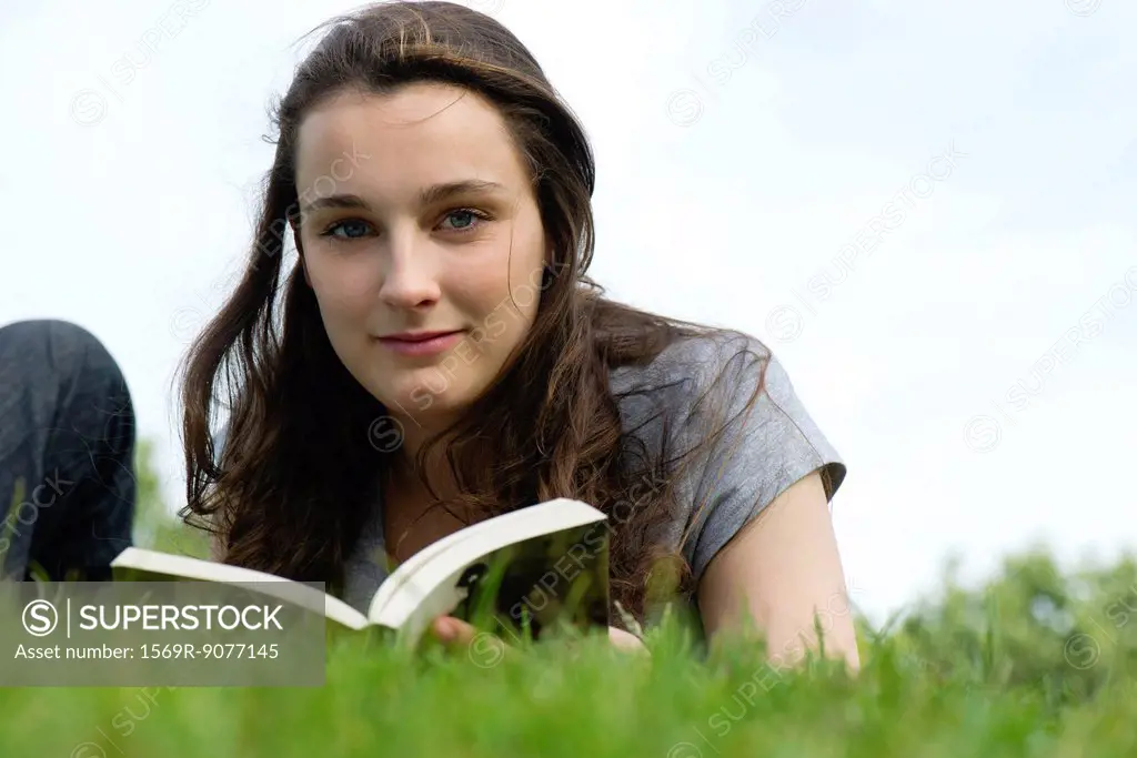 Young woman relaxing outdoors with book, portrait