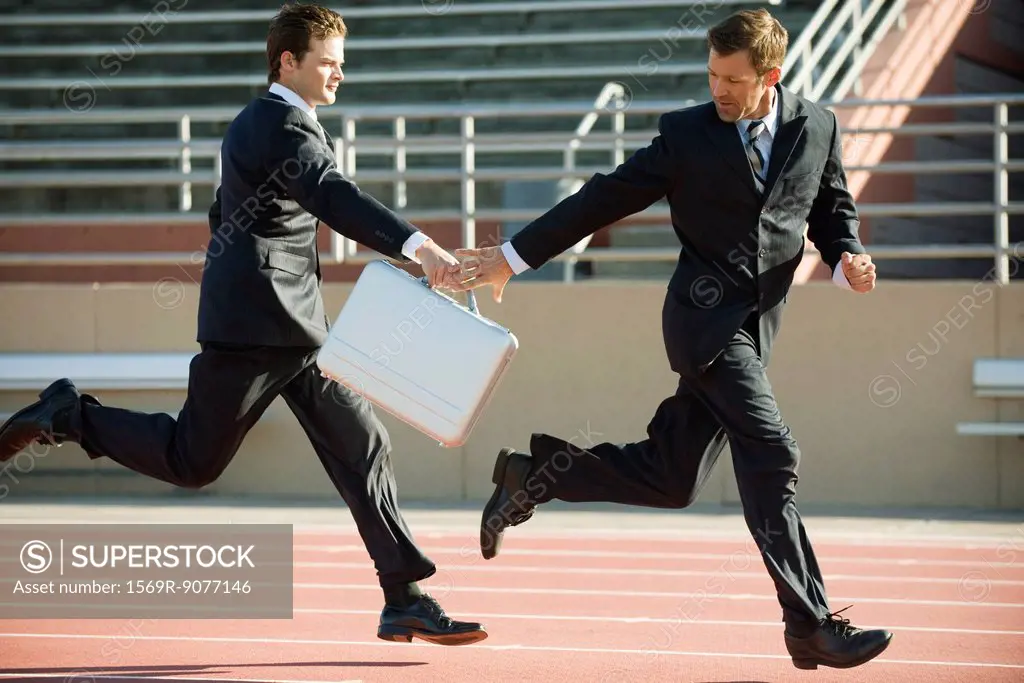 Businessmen handing off briefcase in relay race
